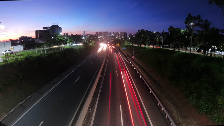 Trail of light caused by vehicular traffic in Highway with buildings from downtown in the background, in Marília