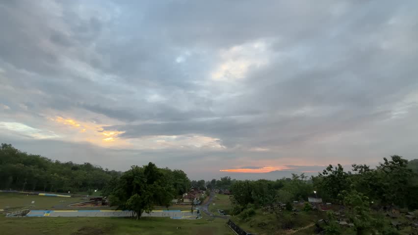 Soft evening sky with gray and orange clouds above a rural field, creating a calm and peaceful atmosphere.