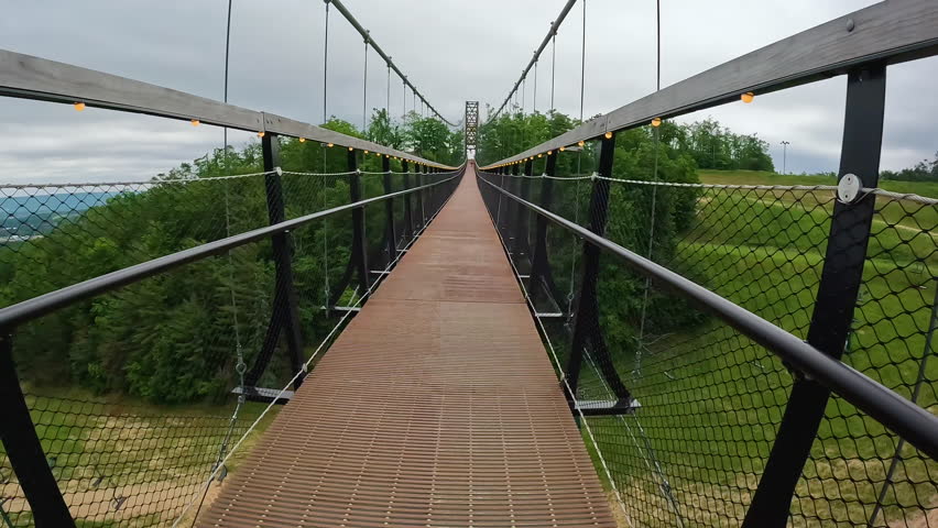Point of view from a person walking along a Suspension Bridge High in the Sky. The bridge connects two mountains with views of the valley below. Located in Northern Michigan, USA.
