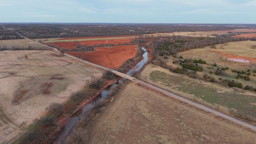 Fly over aerial drone shot of an Oklahoma scene - seasonal series #2 (winter 2) central Oklahoma red soil farmland, winding river, and soft winter light. this scene is documented as the seasons go by.