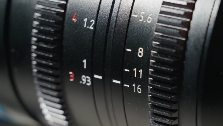 Close up shot of professional camera lens with focus distance and aperture dial and grip wheel. The aperture wheel rotating slowly adjusting the aperture number. 