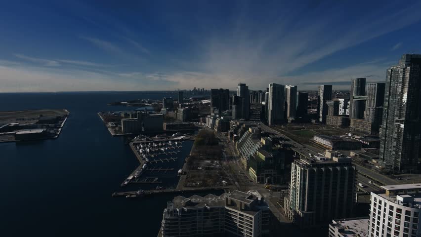 Drone Aerial of Toronto Coastal Waterfront Skyline at Midday featuring the CN Tower, Rogers Centre, Harbourfront, and the shoreline of Lake Ontario.