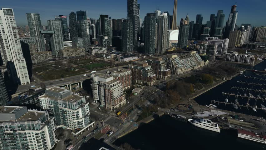 Drone Aerial of Toronto Coastal Waterfront Skyline at Midday featuring the CN Tower, Rogers Centre, Harbourfront, and the shoreline of Lake Ontario.