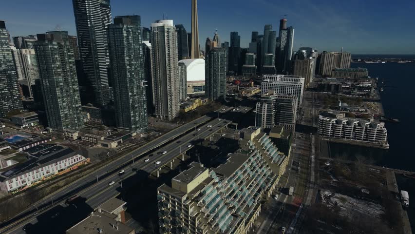 Drone Aerial of Toronto Coastal Waterfront Skyline at Midday featuring the CN Tower, Rogers Centre, Harbourfront, and the shoreline of Lake Ontario.