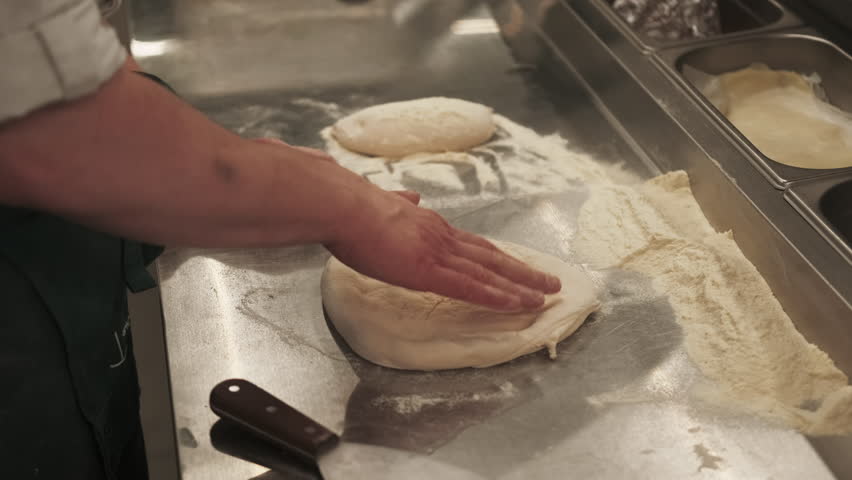 Making dough. Pizza cooking. Skilled chef hand tossing stretching spinning wheat base on metal table. Italian traditional cuisine restaurant.