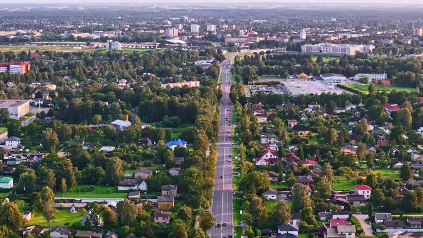 Aerial view of long tree-lined street in Jelgava, Latvia with evening traffic