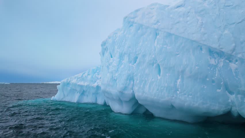 Close view of melting iceberg in wavy water in cloudy Greenland