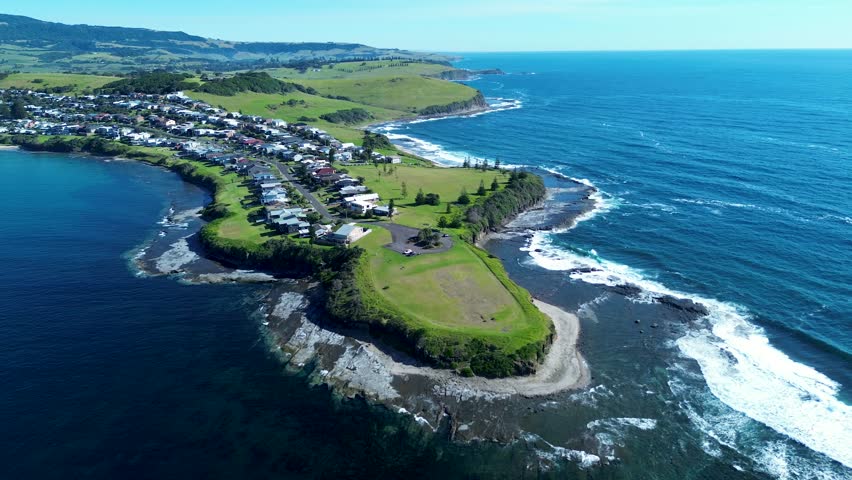 Drone aerial landscape of Gerroa rural town coastline headland with ocean waves crashing on rocky reef beside housing on street suburb in Illawarra South Coast Kiama Australia tourism travel outdoors