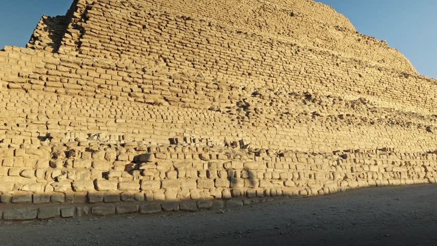 The Step Pyramid of Djoser in the Saqqara necropolis, Egypt, bathed in the warm, golden light of the setting sun.