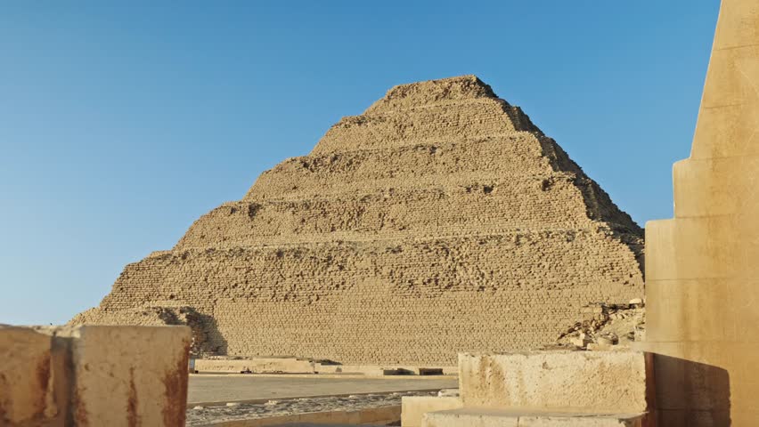 the Step Pyramid of Djoser in the Saqqara necropolis, Egypt, bathed in the warm, golden light of the setting sun.