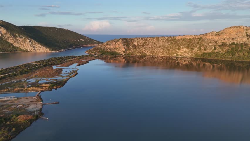 Navarin,Messinia,Gialoval Beach,Aerial view circular pan left from Gialova Lagoon to the Beach.A little channel in between. Lot of sailboats on anchor at the calm bay during sunset.Reflection of cloud