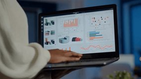Back view of an African businesswoman analyzing financial statistics on a laptop, focusing on business analytics, data review, and professional workflow. - Powered by Shutterstock - Get 15% off with code: PIKWIZARD15
