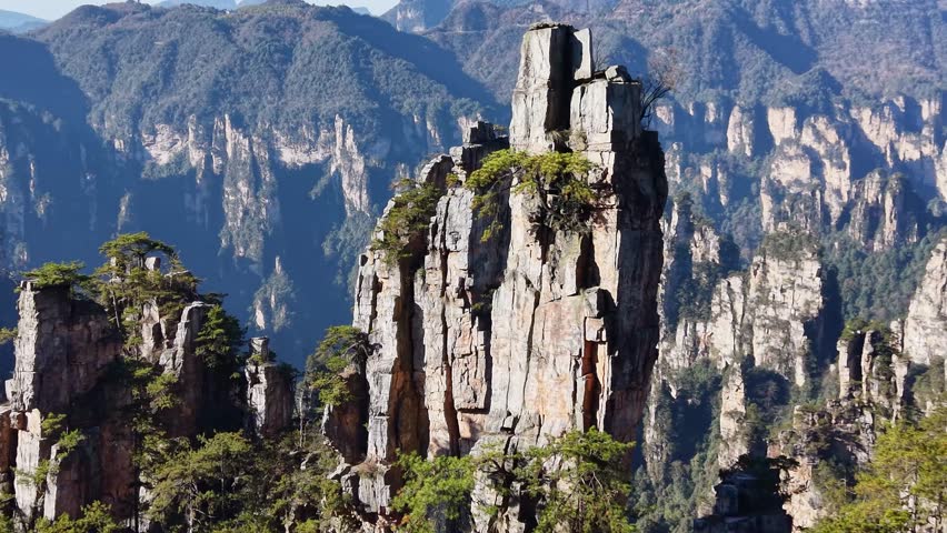 Solitary rock pillar with trees on top surrounded by Zhangjiajie Avatar mountains