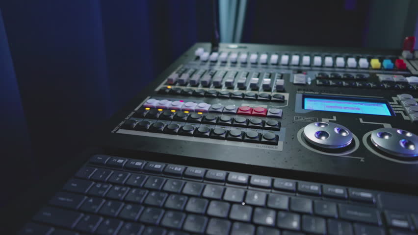 Close-up Of A Professional Digital Lighting And Sound Control Board With Numerous Buttons, Faders, And A Bright LCD Screen Operating In A Dark Studio Environment, Real-time Footage.