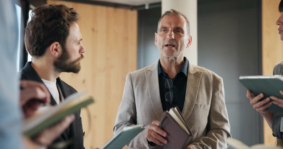 Manager, training group and notebook in discussion for company policy, orientation or job overview. Interns, mature person or office induction with introduction, onboarding or employee responsibility