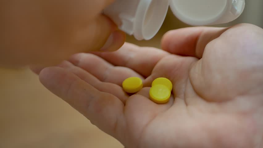 Bottle of yellow pills tipped over spilling onto man hand. Health and treatment options for daily care