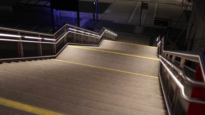 Empty stairway at evening railway station with modern lights metal railings and clean geometry showing calm urban transport atmosphere and safe pedestrian infrastructure at night