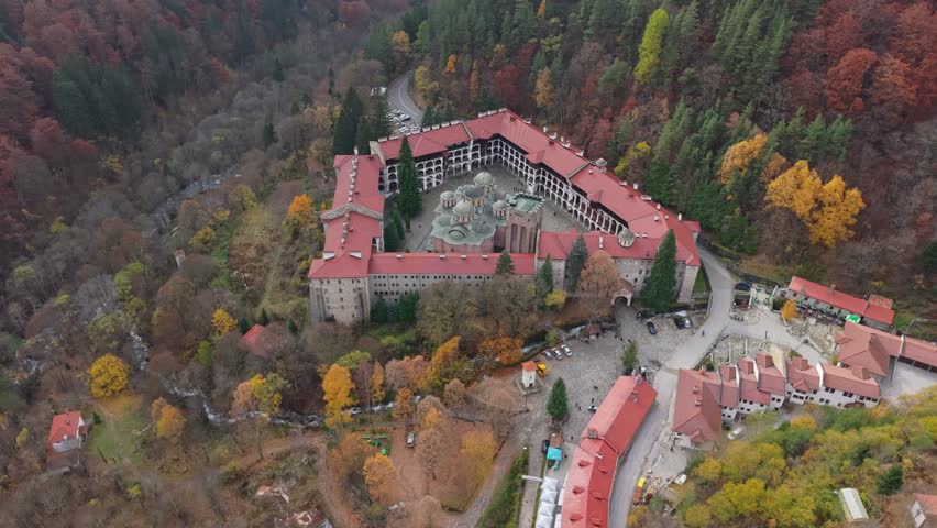 A drone orbits above Rila Monastery, showcasing its unique location and the surrounding breathtaking landscape