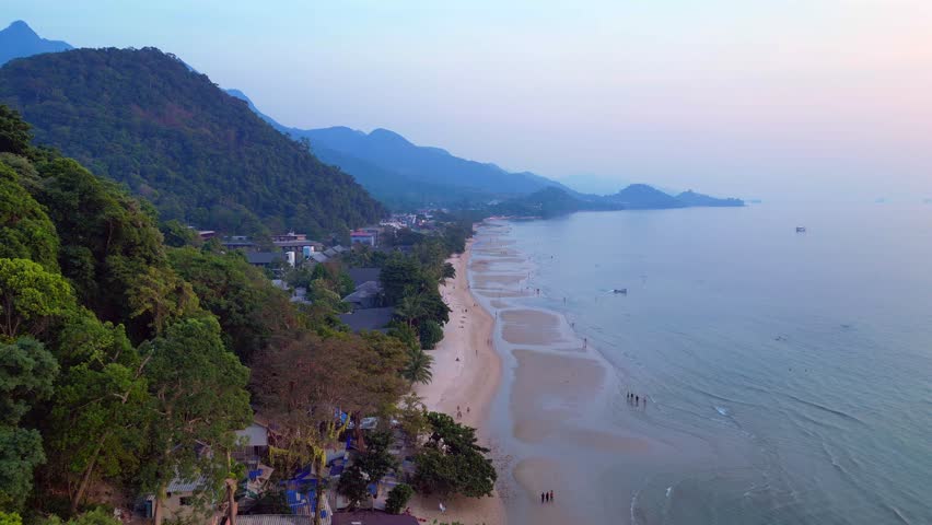White Sand Beach at Koh Chang island, green mountain jungle along the calm turquoise sea. Smooth aerial view