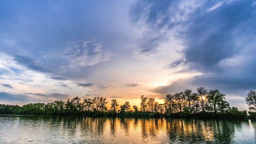 cloud time lapse over tree and lake at sunset time