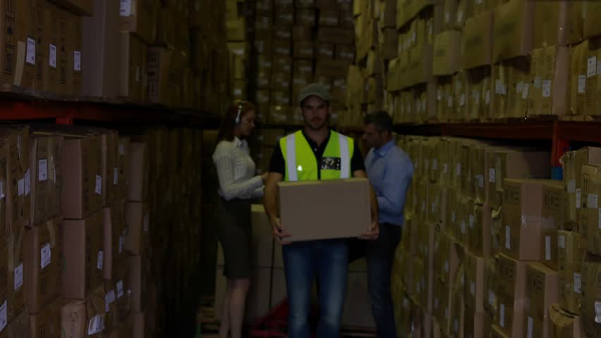 Male worker walking warehouse with box, approach causing network expanding over him mapping stock. Highviz, aisle, storage, teamwork, industrial, logistics, digital