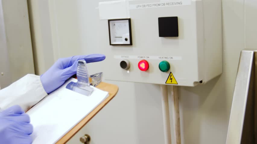 Woman tech noting clipboard, seeing red light, turning knob for lab check, network overlay inactive. Technician, laboratory, gloves, panel, control, monitoring, documentation