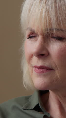 Old Caucasian woman at home trying to see looking in mobile phone screen bad vision blurry eyesight without glasses senior lady aged retired female grandmother with smartphone suffering poor eyesight