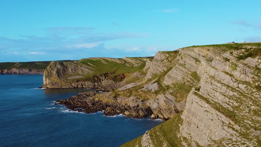 Flying Inbetween Cliffs with Slanting Rock Formations and Grassy Headland. Travel Nature Drone Clip. Beautiful Welsh Gower Peninsula Coast.