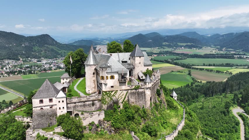 Cinematic drone footage capturing Hochosterwitz Castle on hilltop, fortified walls, dramatic cliffs, summer colors, sweeping aerial movement, historical landmark atmosphere