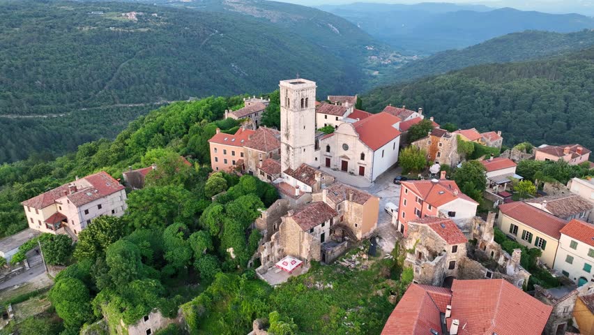 Cinematic aerial drone shot of Oprtalj hilltop medieval town in Istria Croatia during summer with historic stone houses, narrow streets, surrounding hills and authentic European scenery