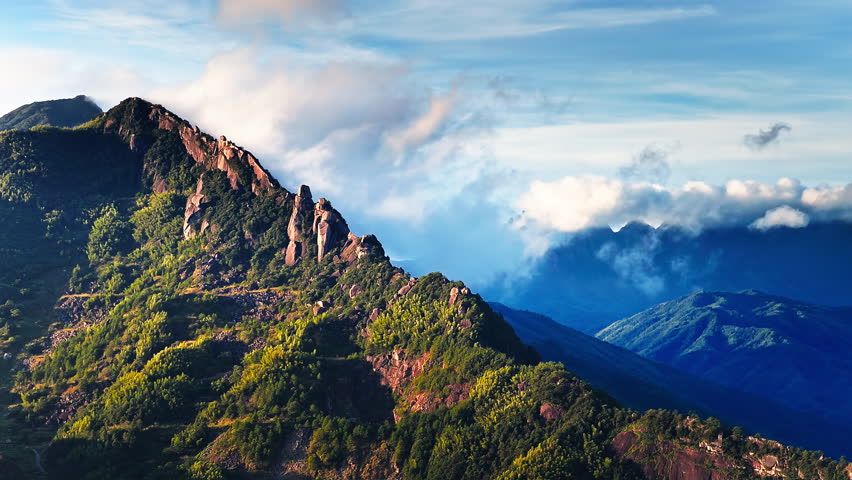 Aerial shot of beautiful rocky mountain ridge with green forest and clouds natural landscape in the morning