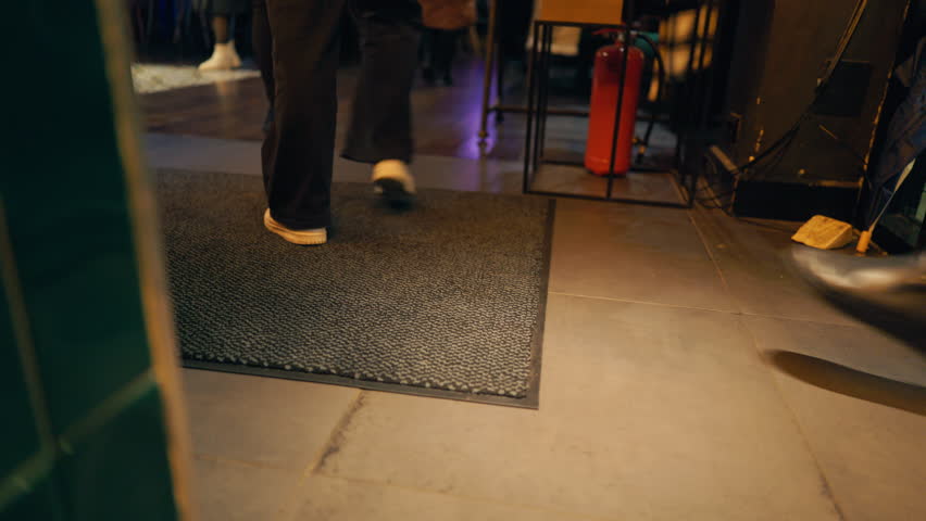 City transit captured during nighttime hours, People passing through with luggage in dim lobby scene