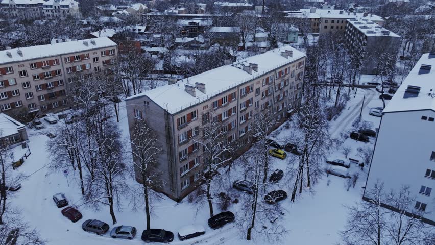 Snow-covered housing blocks reveal post-Soviet architecture in Riga at sunset