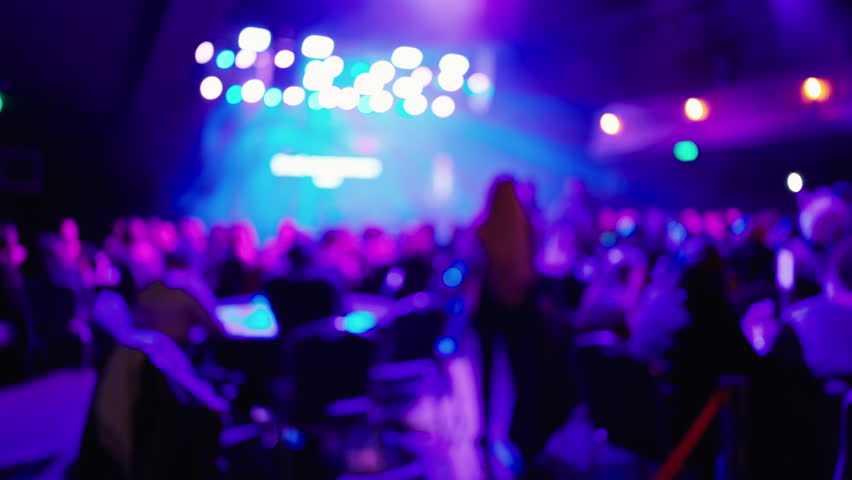 Casual networking under purple lights, Informal professional meetup with vibrant stage lighting