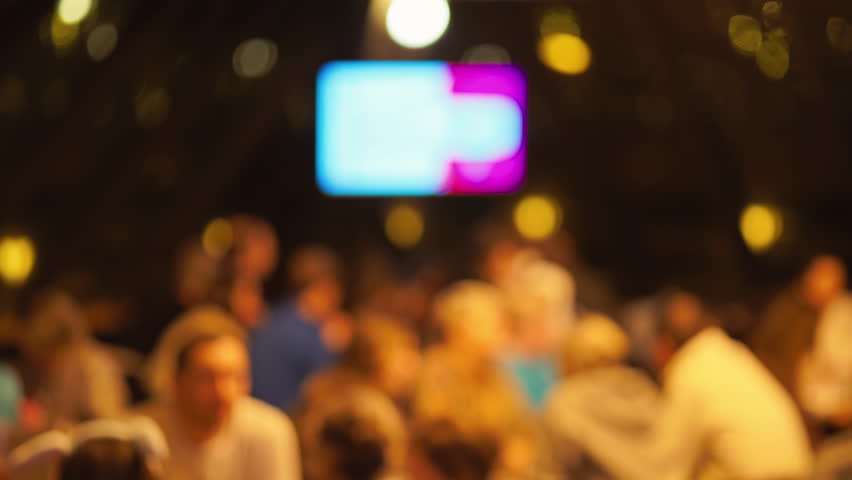 Vague presentation with audience reactions, Obscure product introduction scene with active spectators