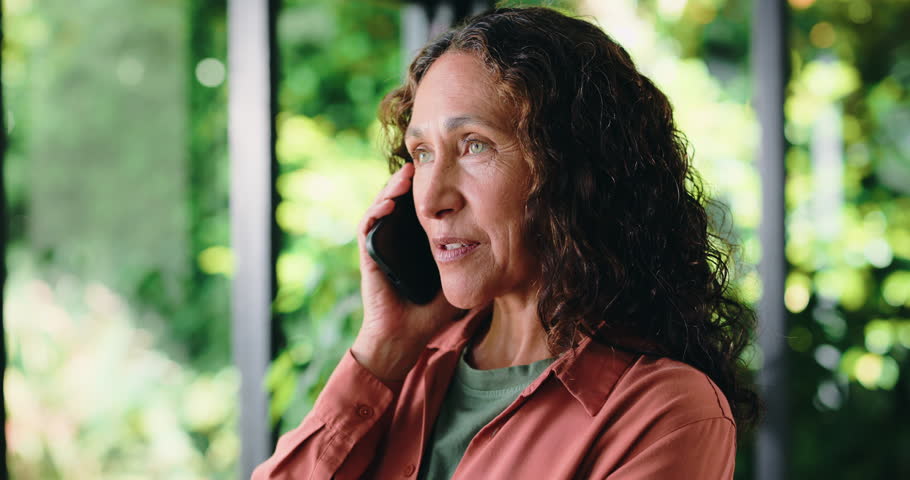 Laughing, phone call and thinking with woman in home conservatory for conversation or humor. Communication, mobile and talking with funny mature person in green sunroom for comedy or reaction