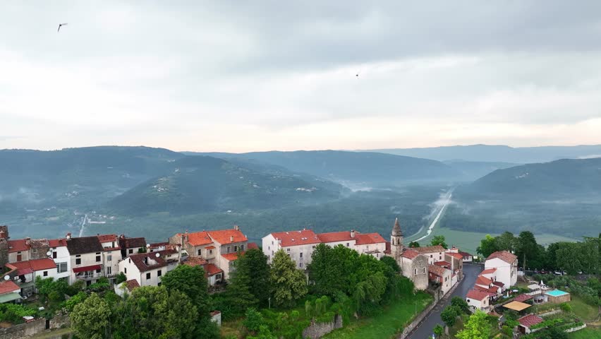 Cinematic drone footage of Motovun medieval town on hilltop in Istria Croatia during early summer with stone houses, green valley, vineyards and authentic European heritage landscape