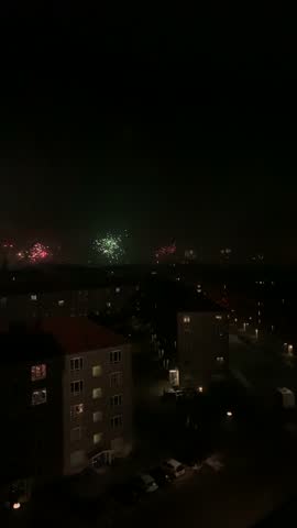 Fireworks Exploding Over City at Night; night video capturing multiple fireworks bursting across the dark sky above a cityscape