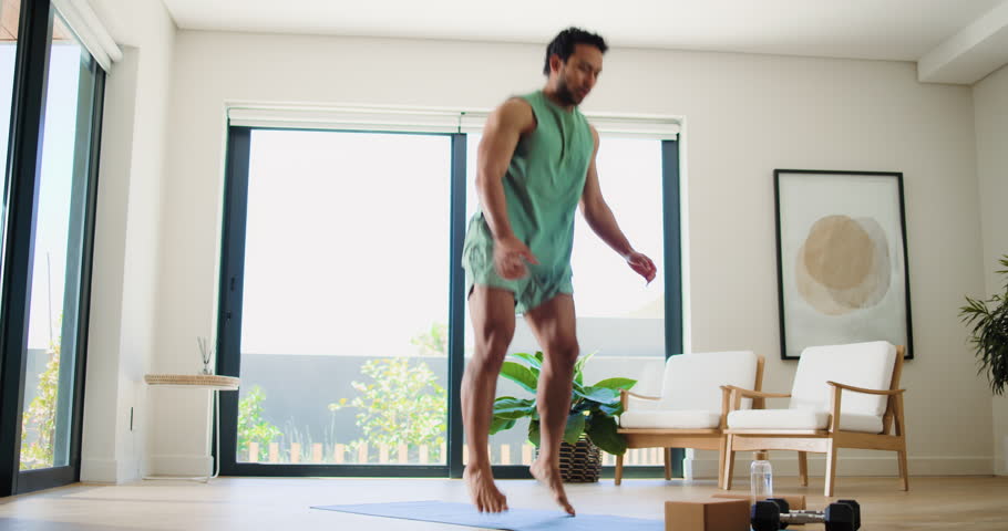 Active, fitness and jump with man in living room of home for development, training or workout. Burpees, exercise and wellness with person on floor in apartment for commitment or dedication or health