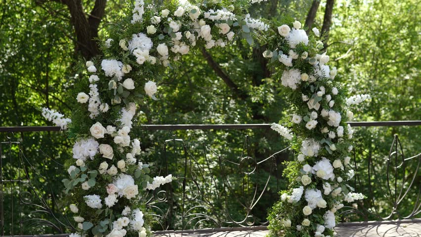wedding arch of white rose flowers on the nature before the wedding ceremony of the bride and groom, festive romantic decor