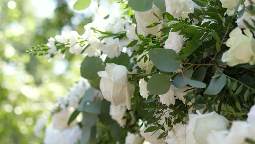 wedding arch of white rose flowers on the nature before the wedding ceremony of the bride and groom, festive romantic decor