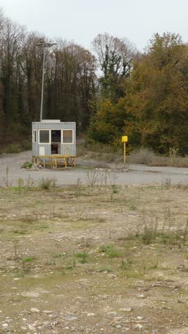 An abandoned guardhouse in the middle of nature in autumn, a panoramic view captured in a vertical frame.