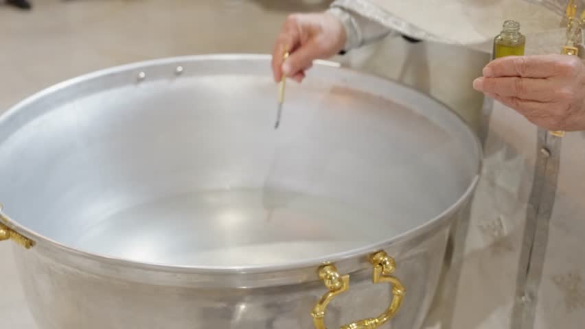 Sacred Ritual For Baptism Conducted, Religious Officiant Handles Vessel And Brush During Sacred Rite, Clergyman Meticulously Mixes Oil And Water To Conduct Baptismal Consecration Ceremony