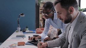 Multiethnic business colleagues discussing a project, using a tablet and taking notes at a desk - Powered by Shutterstock - Get 15% off with code: PIKWIZARD15