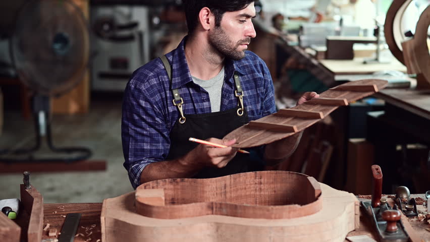 Luthier making top of guitar using traditional tools in workroom with manual tools, arts and craft concept.