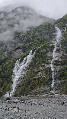 Majestic Cascata di Mondada waterfall cascading down rocky cliffs in Valle Bavona. Misty Swiss alpine landscape ideal for travel promotion.