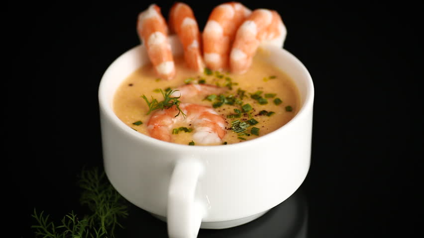 Creamy shrimp soup served in white cup with fresh herb garnish