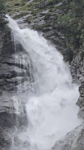 Majestic Cascata di Foroglio waterfall cascading down rocky cliffs in Valle Bavona, Switzerland. Powerful alpine nature surrounded by forest. Ideal for travel ads.