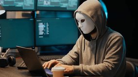 Hacker wearing anonymous mask breaks security system, installing virus to steal online data while hacking network servers late at night. - Powered by Shutterstock - Get 15% off with code: PIKWIZARD15