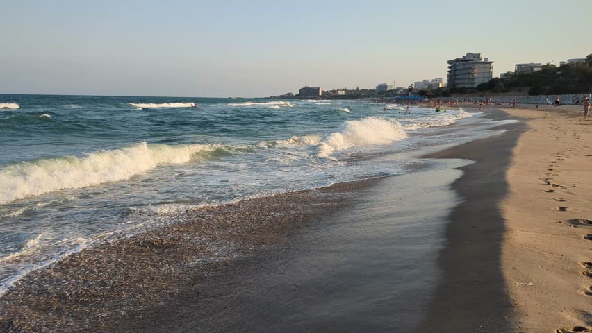 Sea waves shimmer on the sand in afternoon light.